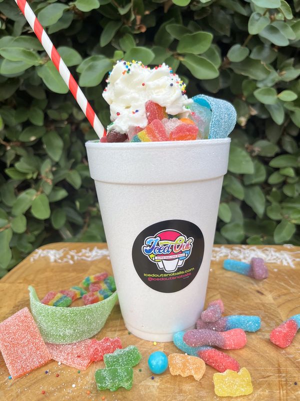 A colorful sno-ball topped with whipped cream and assorted gummy candies.