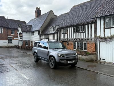 A gray SUV parked on a wet street beside historic half-timbered buildings.