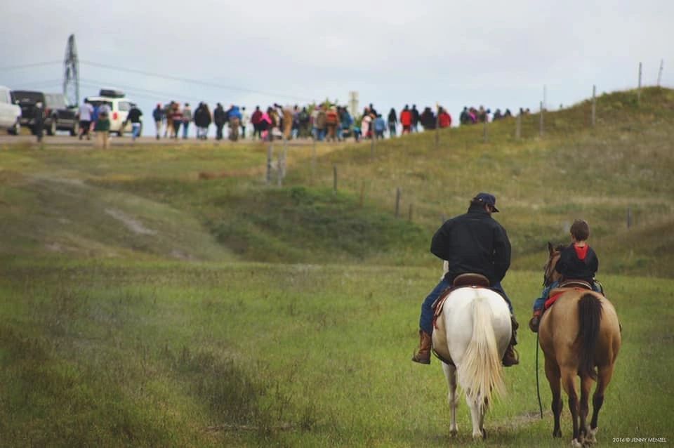 Father and son riding horses to the daily prayer circle at Standing Rock.