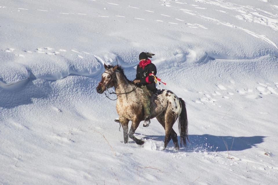 Lakota man riding horse at Standing Rock in the snow.