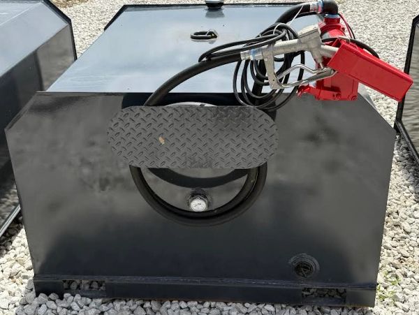 Black fuel tank with hose and nozzle on gravel.
