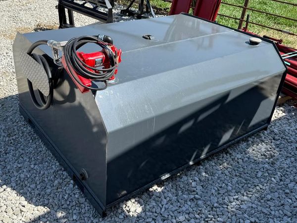 Large black fuel tank with red pump on gravel.