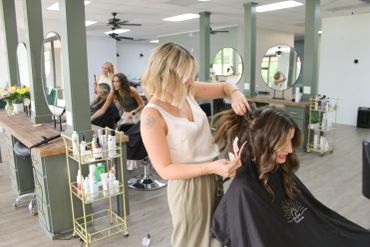 Hairdresser styling a woman's hair in a modern salon.