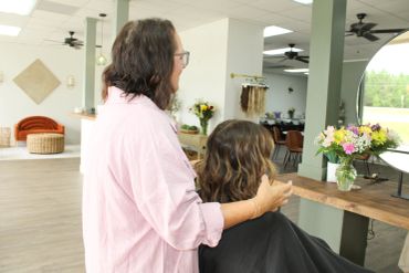 Hair stylist adjusting client's hair in a modern salon.