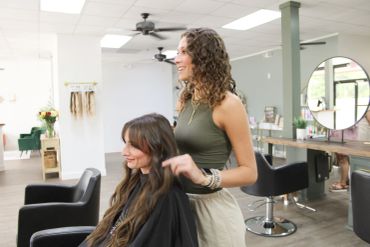 Hairdresser styling a client's hair in a bright salon.