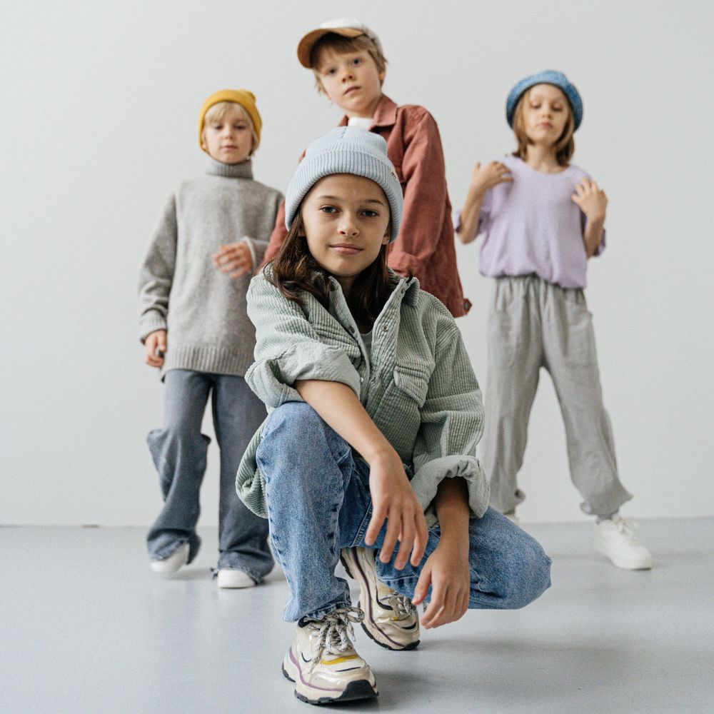 A group of kids posing for a photo. One is in the front squatting down, with three pose behind them.