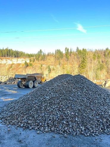 Our river rock pile and haul truck, green trees in the back