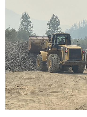 Front end loaded digging into a pile of aggregate to get a scoop. Sky is cloudy