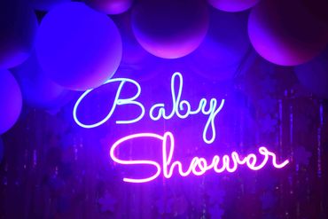 Neon sign reading 'Baby Shower' with purple balloons.