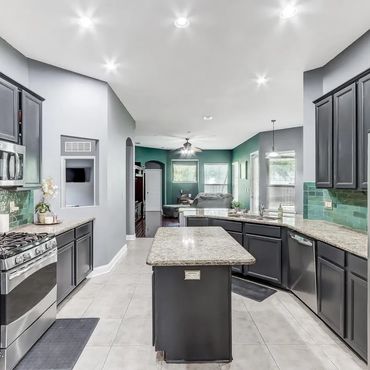 Modern kitchen with dark cabinets, stainless steel appliances, and a central island.