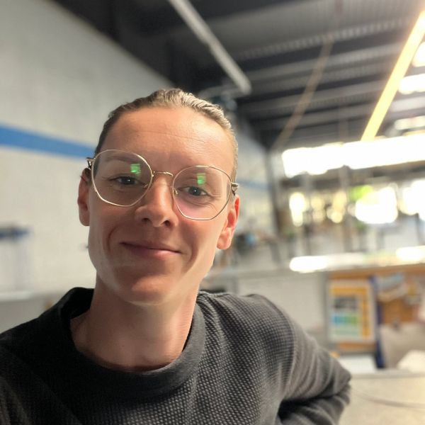 Person with glasses smiling indoors in a modern setting.