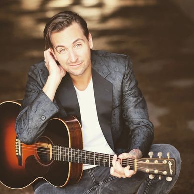 Man playing acoustic guitar, smiling.