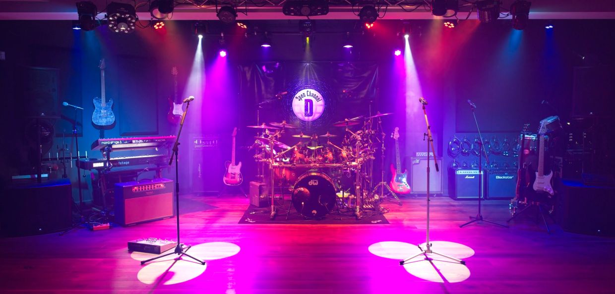 Empty stage with musical instruments under colorful lights.