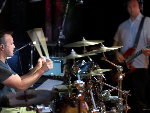 Drummer and bassist performing on stage.
