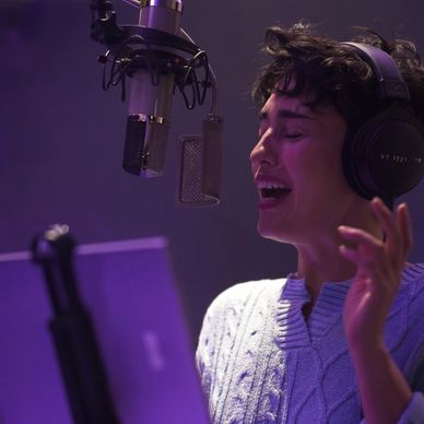 Person singing passionately into a microphone in a studio.
