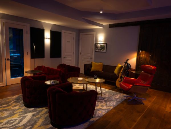 Cozy living room with red chairs and guitar.