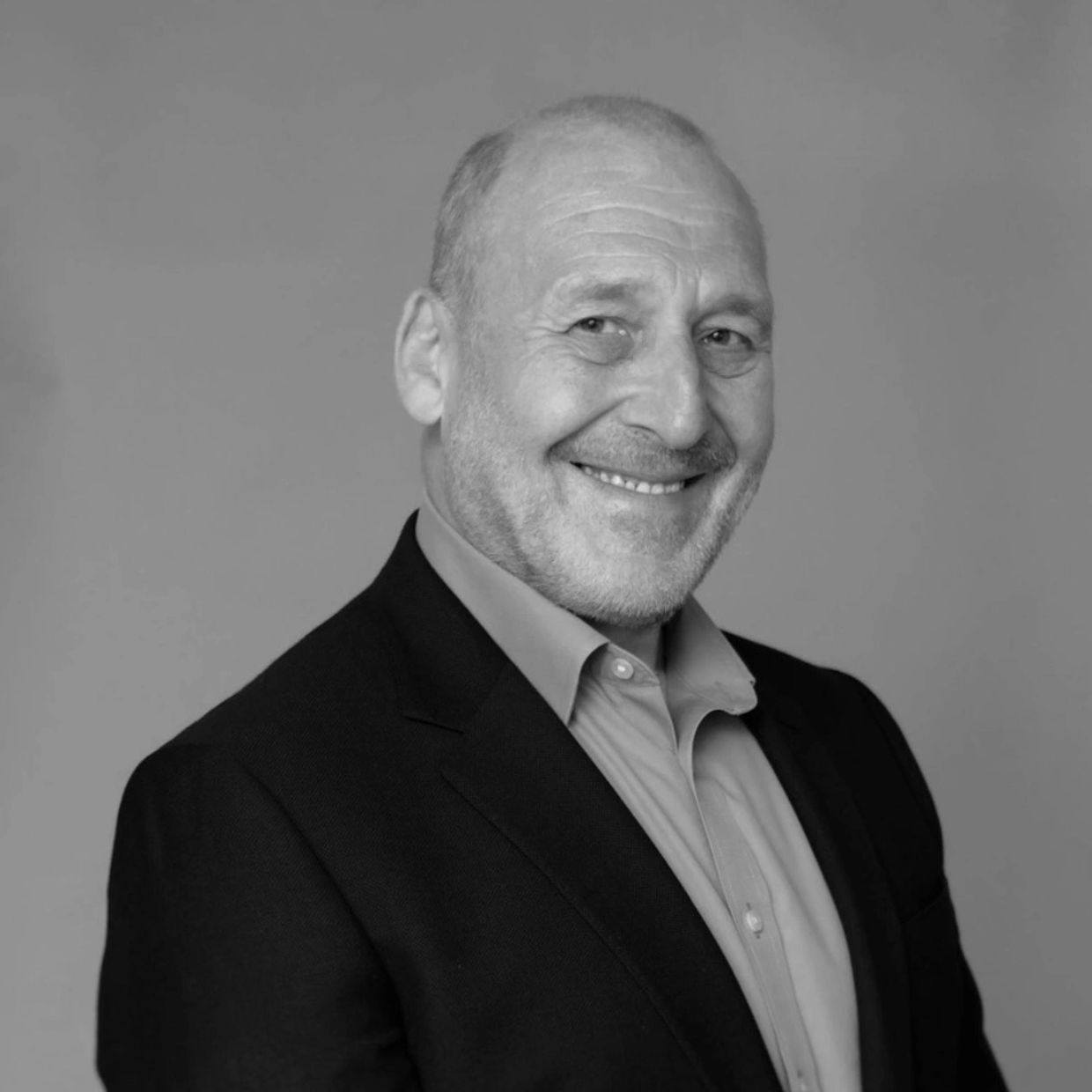 Smiling middle-aged man in a suit against a plain background.