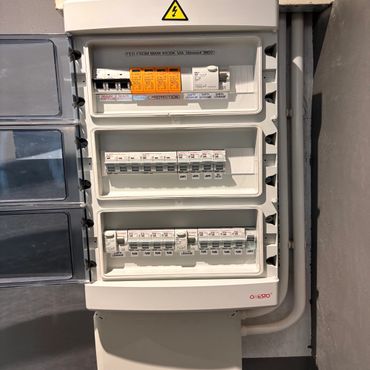 Electrical distribution panel with switches and circuit breakers labeled for lights and plugs.