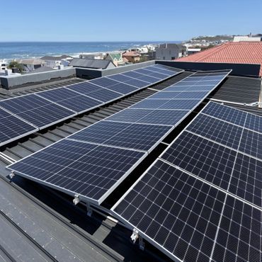 Solar panels installed on a rooftop overlooking a coastal neighborhood.