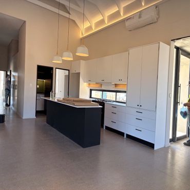 Modern kitchen with black island, white cabinets, and pendant lights under vaulted ceiling.