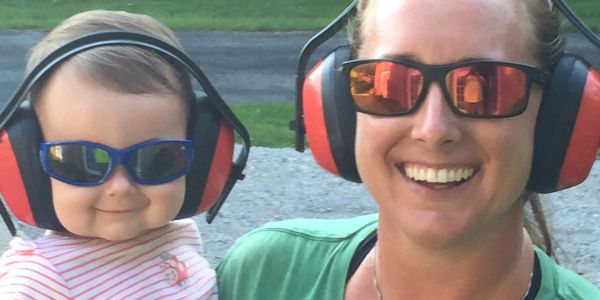 Child and woman with headphones and sunglasses smiling.