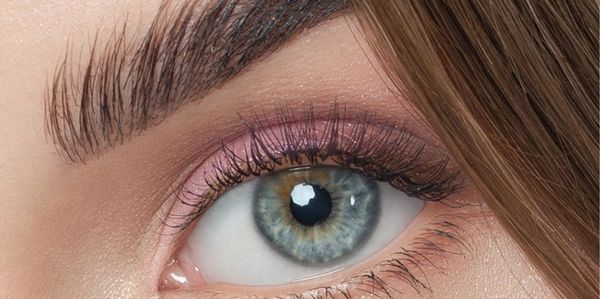 Close-up of a blue-green eye with detailed eyelashes and eyebrow.
