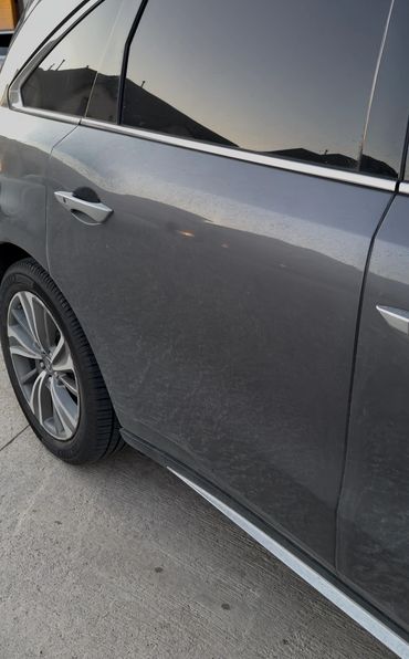 Side view of a gray car with a dirty surface and alloy wheels.