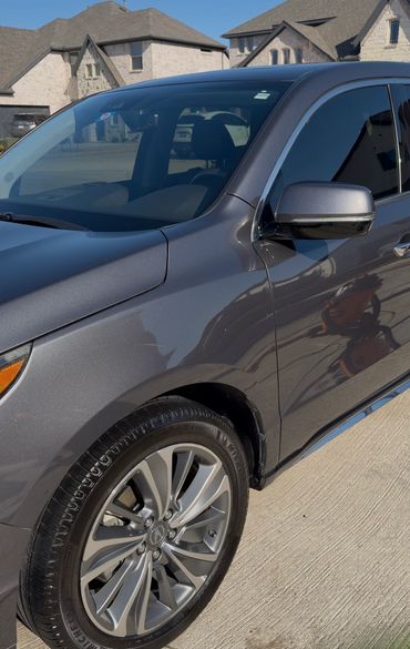 Close-up of a sleek gray car wheel and side mirror on a sunny day.