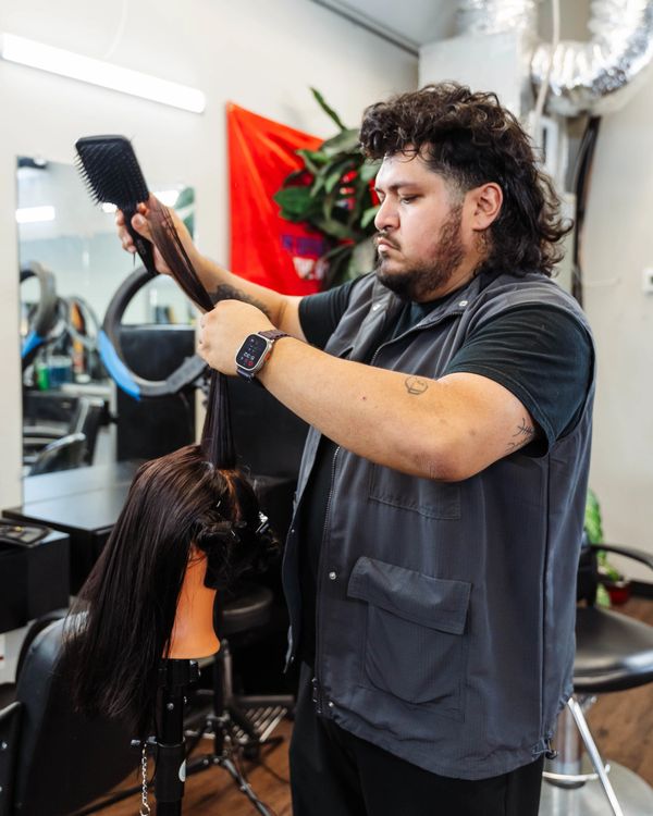 Barber School student practicing hair sectioning on a long-hair mannequin during training.