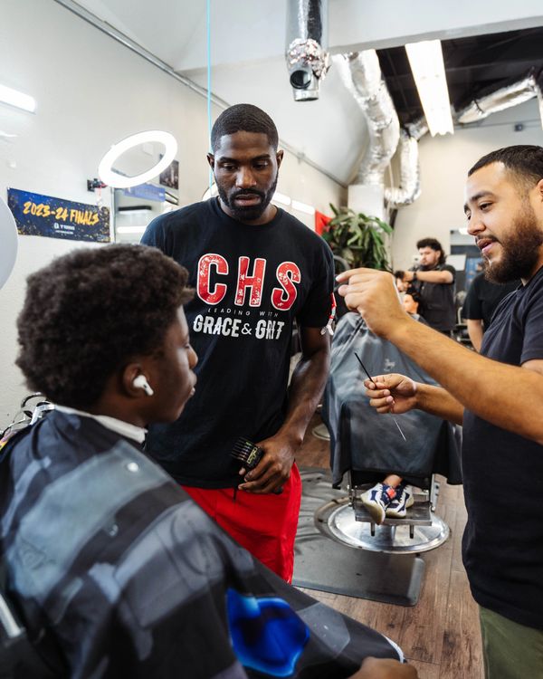 Instructor Alex Carrillo guiding a student through their first haircut at Fade Fellas Barber School.