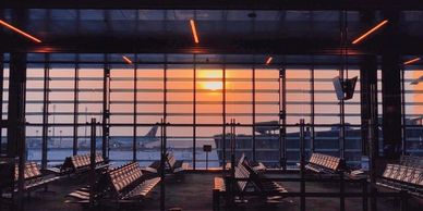 A scene of an empty Hamad International Airport at sunset with a plane outside the window  