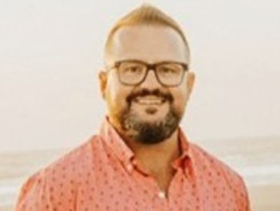 Smiling man wearing glasses and a red shirt.