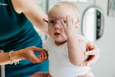 Baby wearing oversized glasses covering one eye.