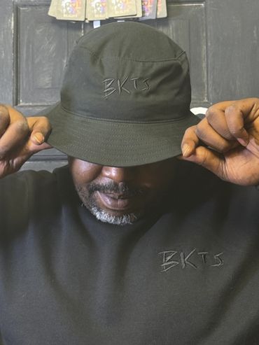 Man wearing a black bucket hat with BKTS embroidered.