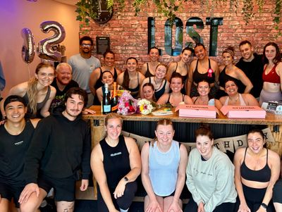 Group of people celebrating indoors with balloons and cakes.