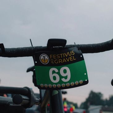 Close-up of a bike handlebar with a Festivus of Gravel race number 69.