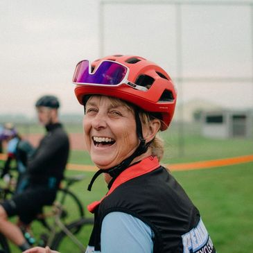Smiling cyclist wearing a red helmet and sunglasses outdoors.