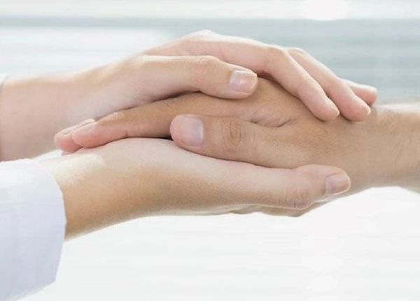Therapist supporting client by hand holding.