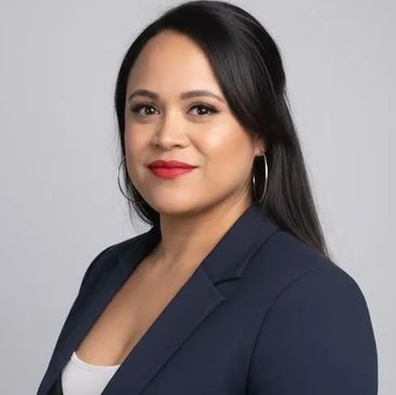 Professional woman with long black hair wearing a navy blazer and red lipstick.