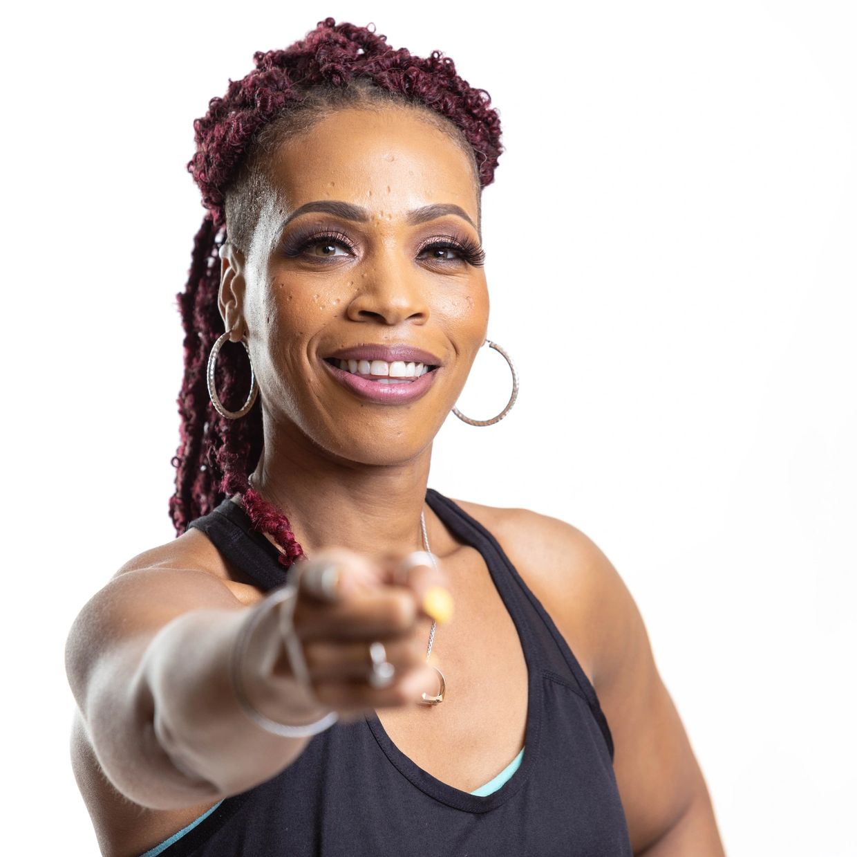 Confident woman with braided hair pointing forward and smiling.