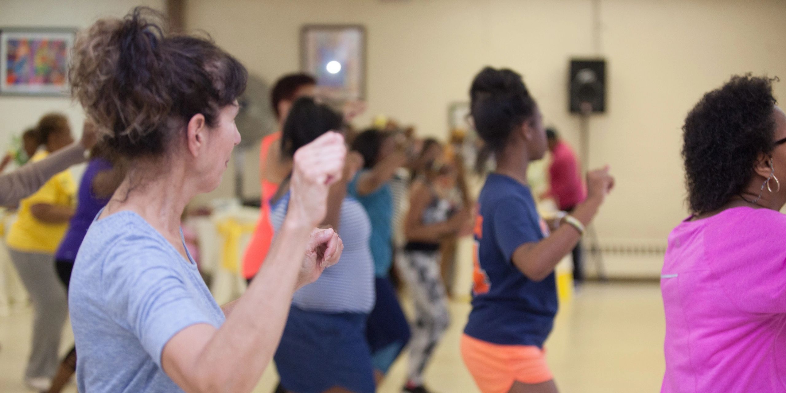 A diverse group of people exercising together indoors in a fitness class.