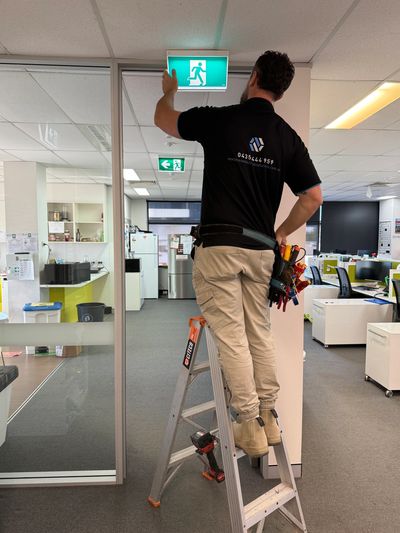 NextPhase Electrical Solutions commercial electrician testing exit light in Mayfield office building