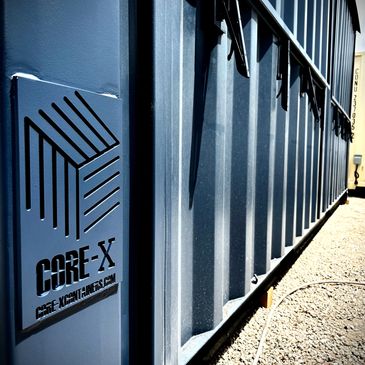 Close-up of a CORE-X branded blue shipping container outdoors.