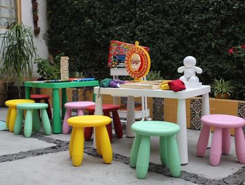 Colorful children's stools and tables arranged outdoors in a playful setting.