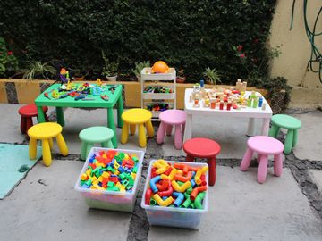 Colorful children's stools and toy tables with building blocks outside.