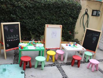 Colorful children's art workshop setup with small stools and easels outdoors.