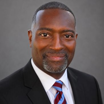 Professional headshot of a man in a suit and tie.