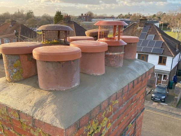 Newly installed chimney cowls on a stack with new cement flaunching