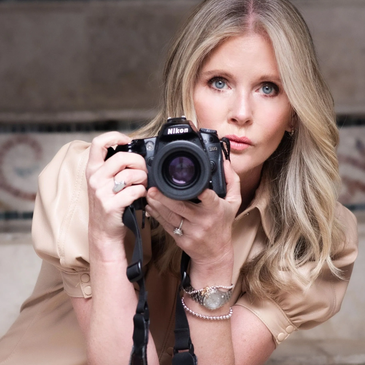 Woman holding a Nikon camera and looking straight.