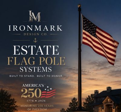 American flag flying on a tall flagpole at sunset by a house.